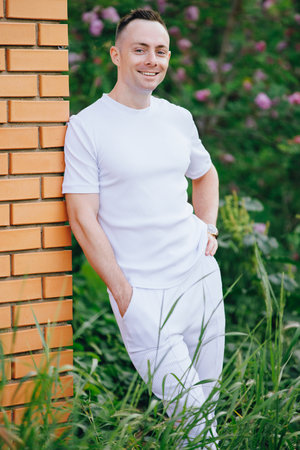 Smiling handsome Caucasian man portrait leaning at wall at summer dayの写真素材