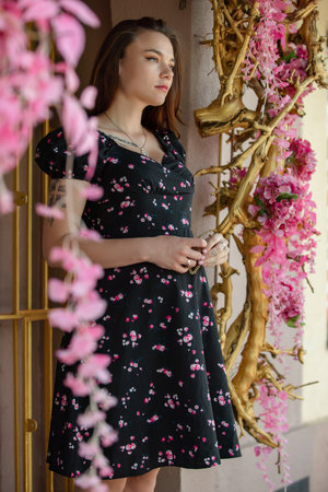 Pretty pregnant woman with little belly in the dress posing near pink decorative flowersの写真素材