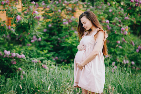 Pregnant woman touching her belly standing at the natureの写真素材