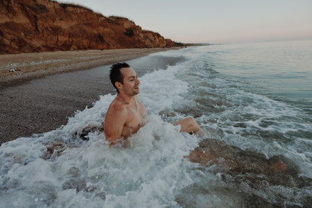 Happy man sitting in the sea wavesの写真素材