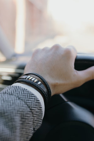 A classical male leather bracelet on a hand in the car
