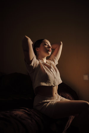 Beautiful woman home creative portrait in low key at the morningの写真素材