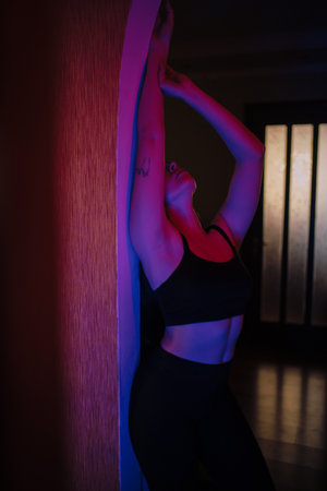Woman posing in purple and blue light near mirrorの写真素材