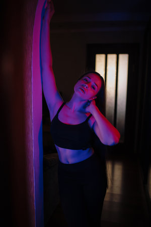 Woman posing in purple and blue light near mirrorの写真素材