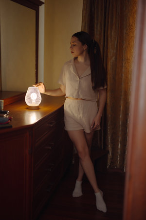 Woman posing near desk lamp at homeの写真素材