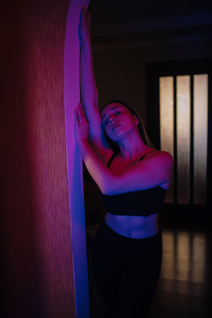 Woman posing in purple and blue light near mirrorの写真素材