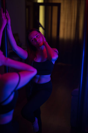 Woman posing in purple and blue light near mirrorの写真素材