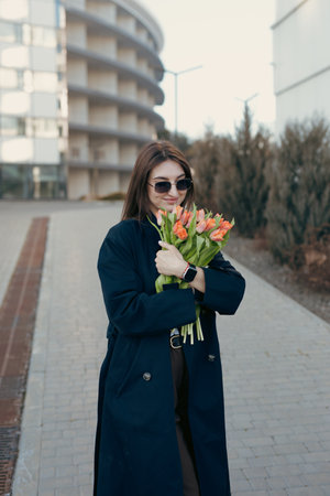 Happy woman sniff flowers in the city street at spring dayの写真素材