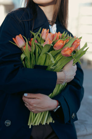 Unrecognizable cropped woman holding a tulip flowers at the city streetの写真素材