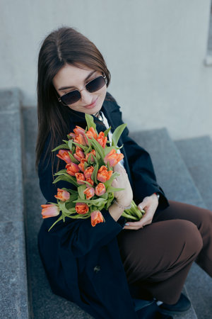 Happy woman holding tulip flowers in the city at spring dayの写真素材