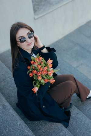 Happy woman holding tulip flowers in the city street at spring dayの写真素材