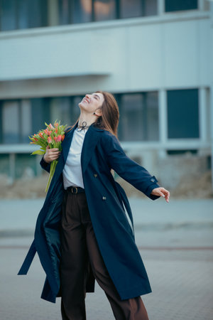 Happy woman turns around with tulip flowers in the city street at spring dayの写真素材