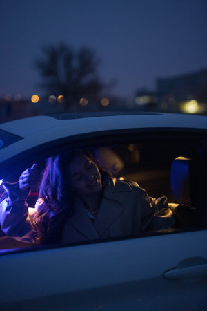 Lady posing in the car in blue light at nightの写真素材