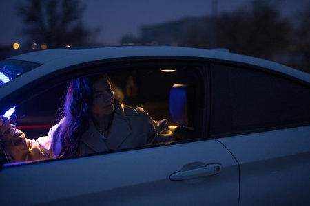 Lady posing in the car in blue light at night