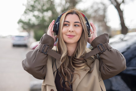 Beautiful woman wearing headphones at the city street listen musicの写真素材