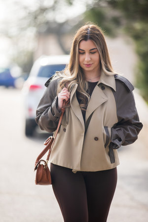 Beautiful woman walking along city street holding bag at the spring dayの写真素材