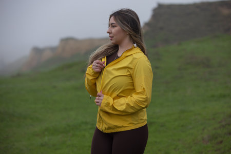 Happy woman enjoy the nature and overcast weather in a yellow jacketの写真素材
