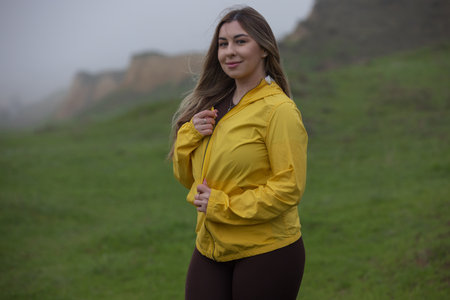 Happy woman enjoy the nature and overcast weather in a yellow jacketの写真素材
