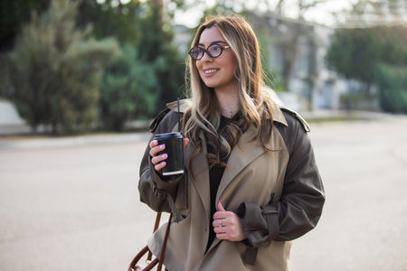 Pretty woman holding coffee cup drinking at the city streetの写真素材