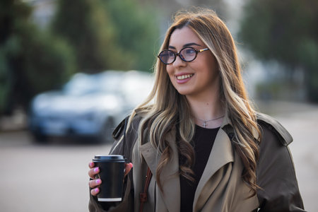 Pretty woman holding coffee cup drinking at the city streetの写真素材