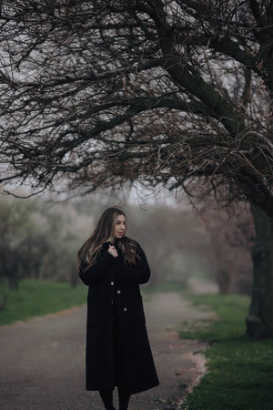Mystic art photo of woman standing under tree at overcast foggy dayの写真素材