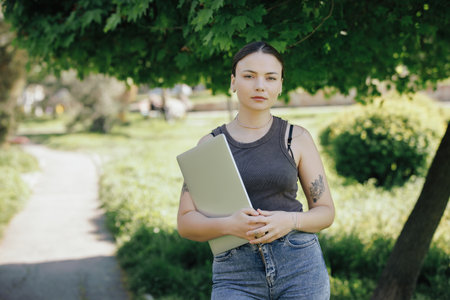 Woman office worker holding a laptop in the parkの写真素材