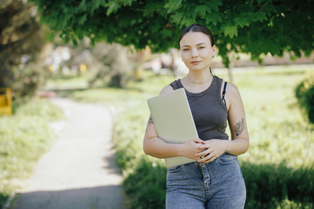 Woman office worker holding a laptop in the parkの写真素材