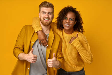 Horizontal shot of satisfying mixed race couple laughs happily, leans at the shoulder of boyfriend,...