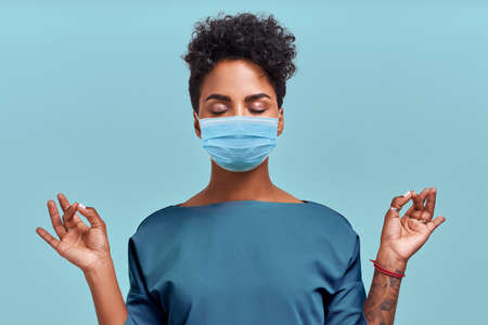 African American doctor meditation wear respiratory mask, no stress free relief at work concept,...