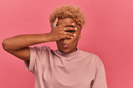 Omg, I dont want to see it. Young African American woman peeks through fingers covering face with...