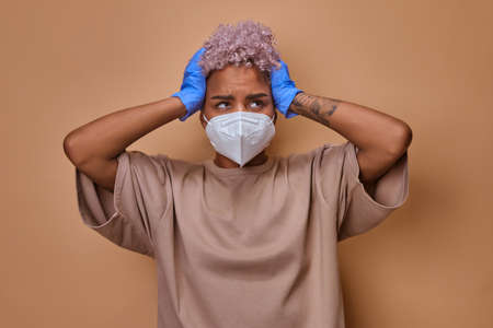 Annoyed woman with face mask grabbed head feeling worried about epidemic.