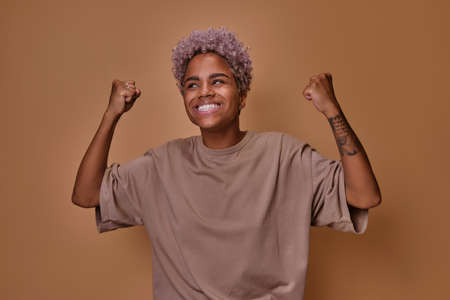 Young African American woman rejoices and dances celebrating achieving goalsの写真素材