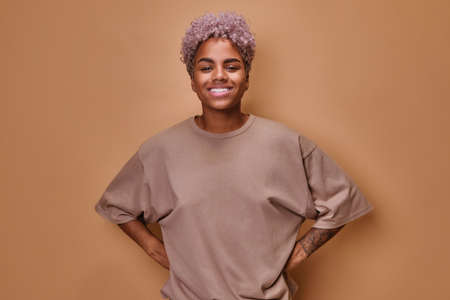 Young African American woman with curly hairstyle smiles and looks at cameraの写真素材