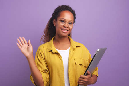 Young African American woman freelancer waving hand and holding laptopの写真素材