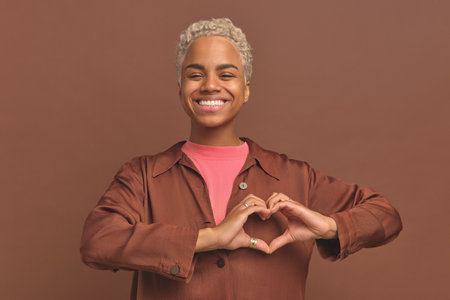 Young African American woman shows heart with hands for romantic confessionの写真素材