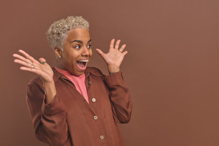 Young positive surprised African American woman shouts and waves handsの写真素材