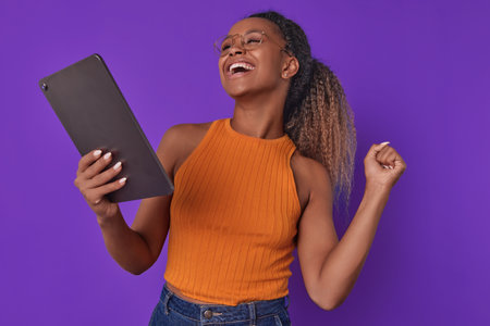 Young cheerful African American woman freelancer holding electronic tabletの写真素材