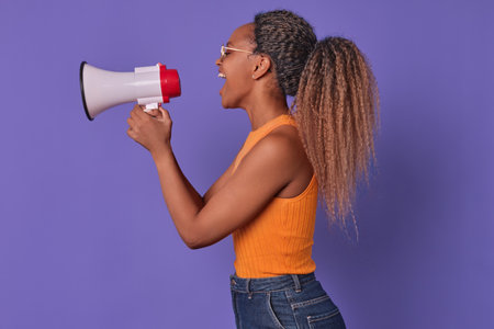 Young eccentric ethnic African American woman stands sideways with megaphone