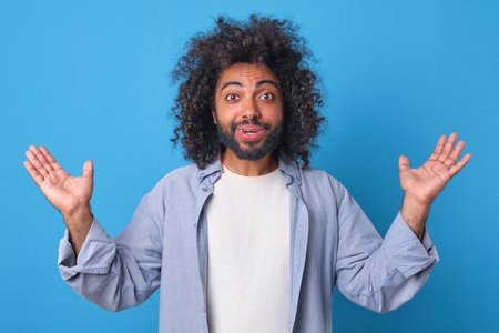 Joyful man expressing excitement with open arms against a bright blue backdropの写真素材