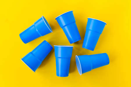 Vibrant blue plastic cups upside down on yellow background. Closed composition image. Top view. No plastic and eco concept.の写真素材