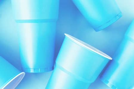 Bright blue neon plastic cups on blue background. Close up flatlay. No plastic eco conceptの写真素材