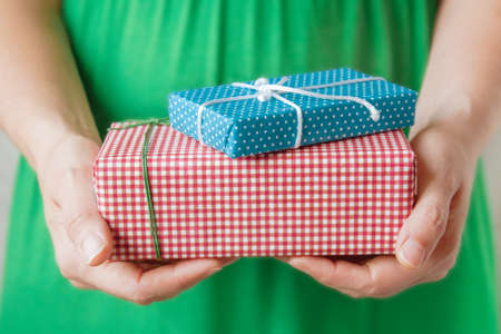 Woman in green dress holding small handmade gifts in decorated craft paper in hands. Selective...