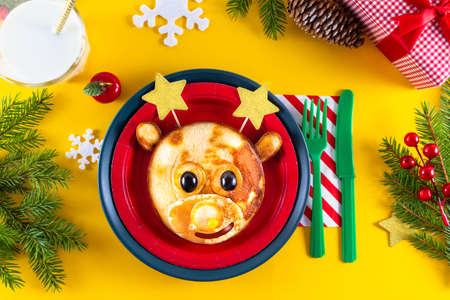 Creative christmas snack for children with xmas deer. Cute elk shaped pancakes, berries and chocolate sauce. Artistic breakfast served in plate.の写真素材