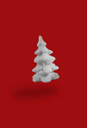 Floating christmas concept. White plastic fir falling on red background. Trendy levitation tree.の写真素材