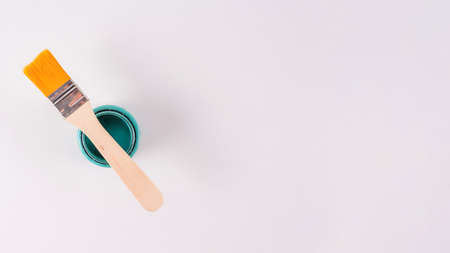 Top view of small brush with wooden handle and green watercolor paint in newly opened can tin on bright background. Copy space. Painter house ideas. Banner format.の写真素材