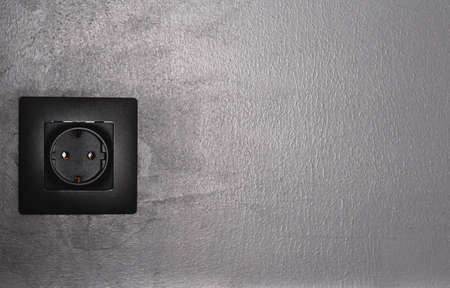 Minimal black in home interior. Copy space. Conceptual trendy electric socket on black matte wall.の写真素材