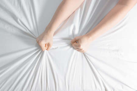 Woman's hands are visible from under the covers as a symbol of fight against insomnia. Tired and...