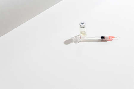 Close-up glass ampoule with medicine and single-use syringe ready for use. Light sterile background....