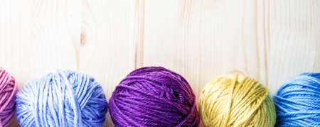 Multicolored woolen balls on wooden background. Banner with botten border. Knitting as hobby....
