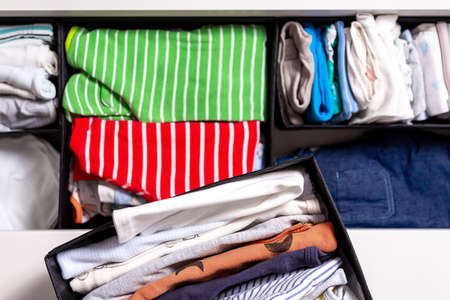 Kid's clothes in black box on chest of drawers. Top view. Close up. Children's wardrobe and storage....